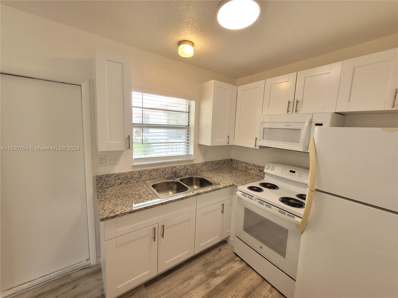 a kitchen with granite countertop cabinets and white appliances