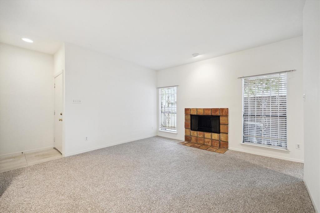 an empty room with a fireplace and natural light