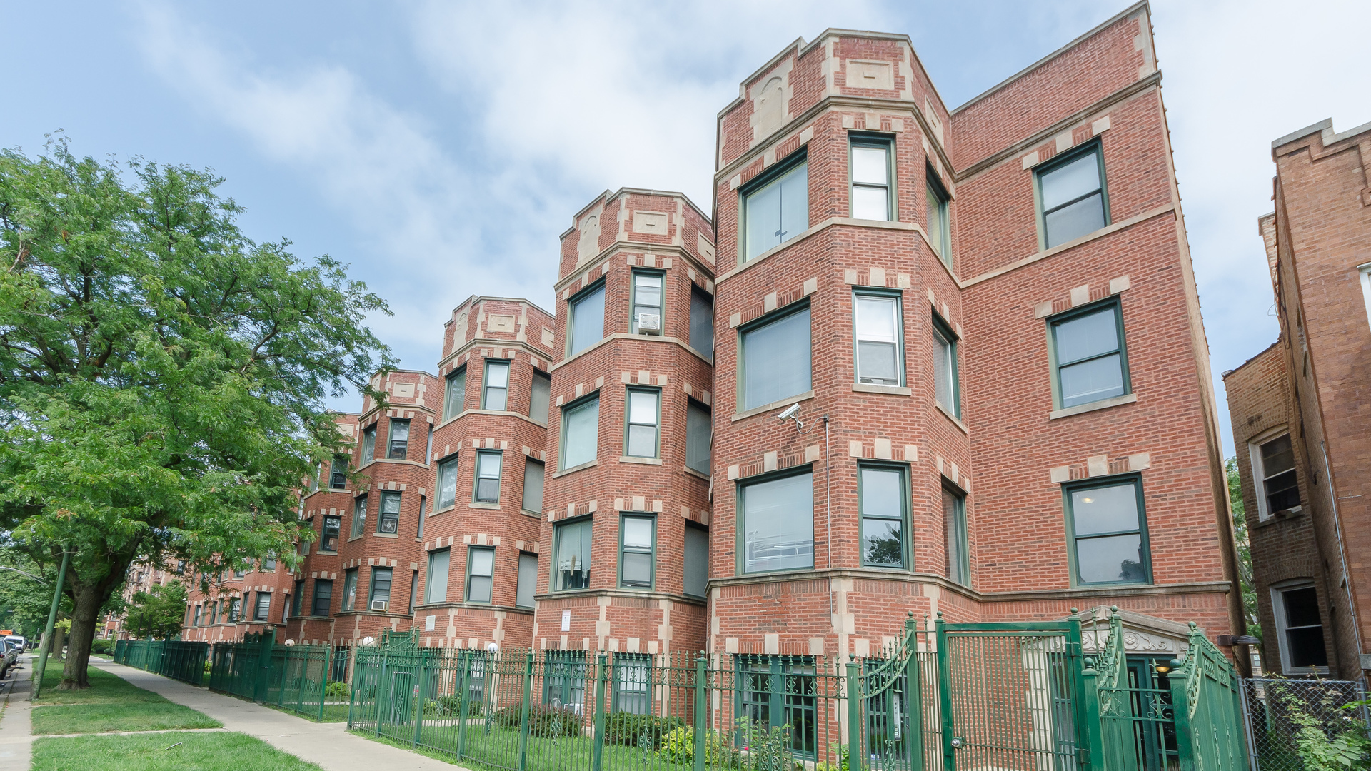 a front view of a multi story residential apartment building with yard and trees