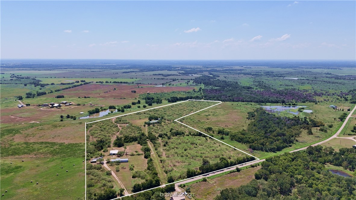 an aerial view of a residential houses with outdoor space and trees