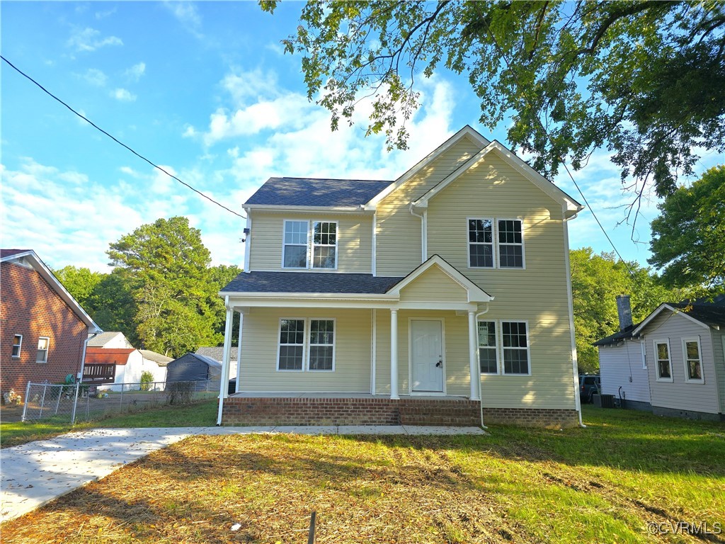 View of front of home with a front yard and a porc