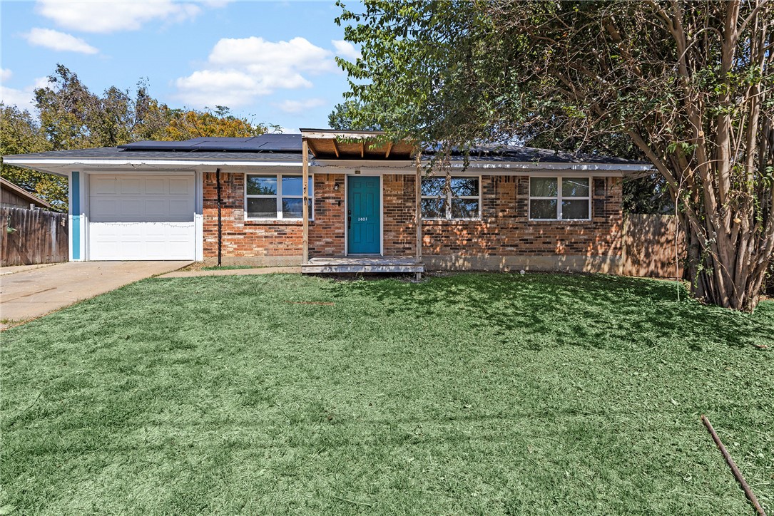 Ranch-style house with a garage, solar panels, and