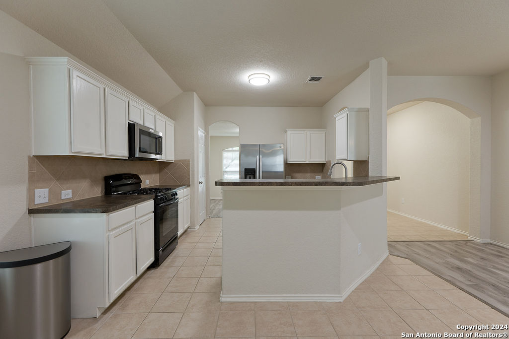 a kitchen with stainless steel appliances granite countertop a refrigerator a stove top oven a sink and dishwasher