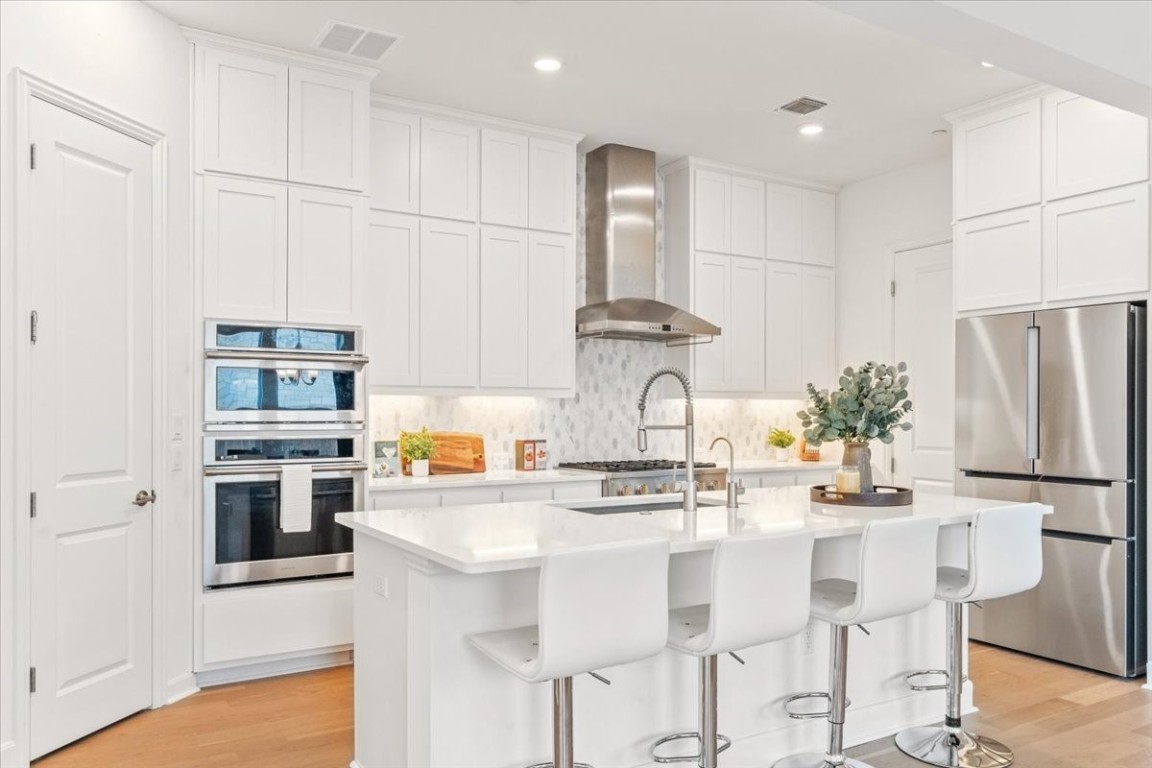 a kitchen with stainless steel appliances kitchen island granite countertop a refrigerator and a stove top oven