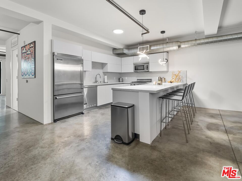 a kitchen that has a lot of cabinets in it and stainless steel appliances