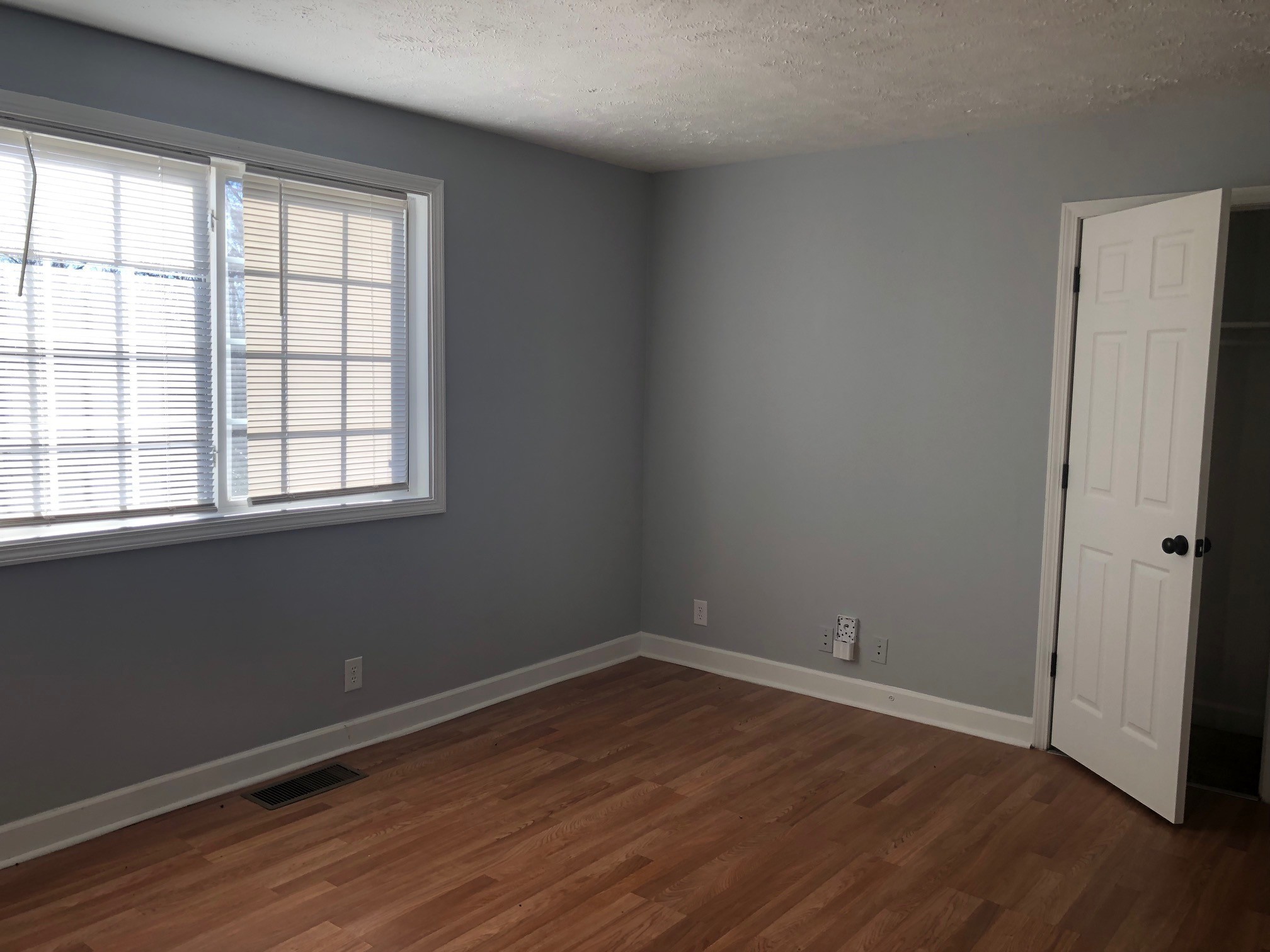 an empty room with wooden floor and windows