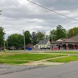 a view of a big white house with a big yard and trees