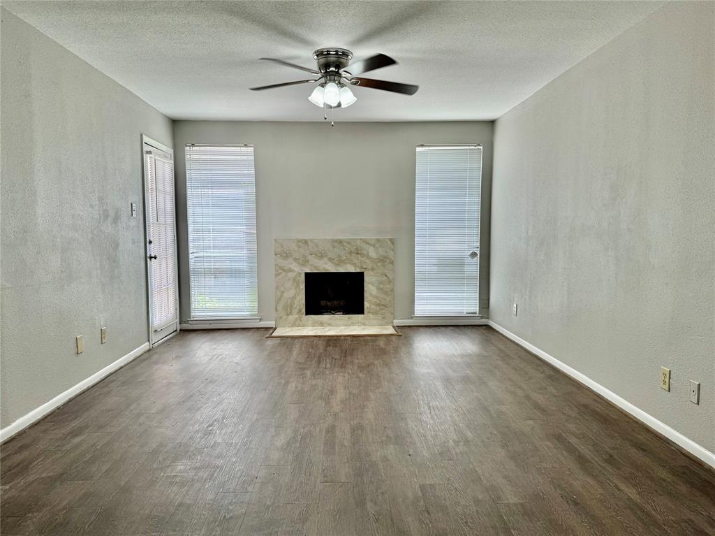 an empty room with chandelier fan and windows