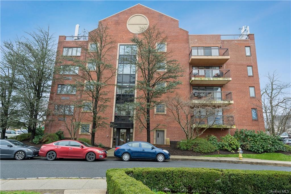 a front view of a building with lot of cars and trees