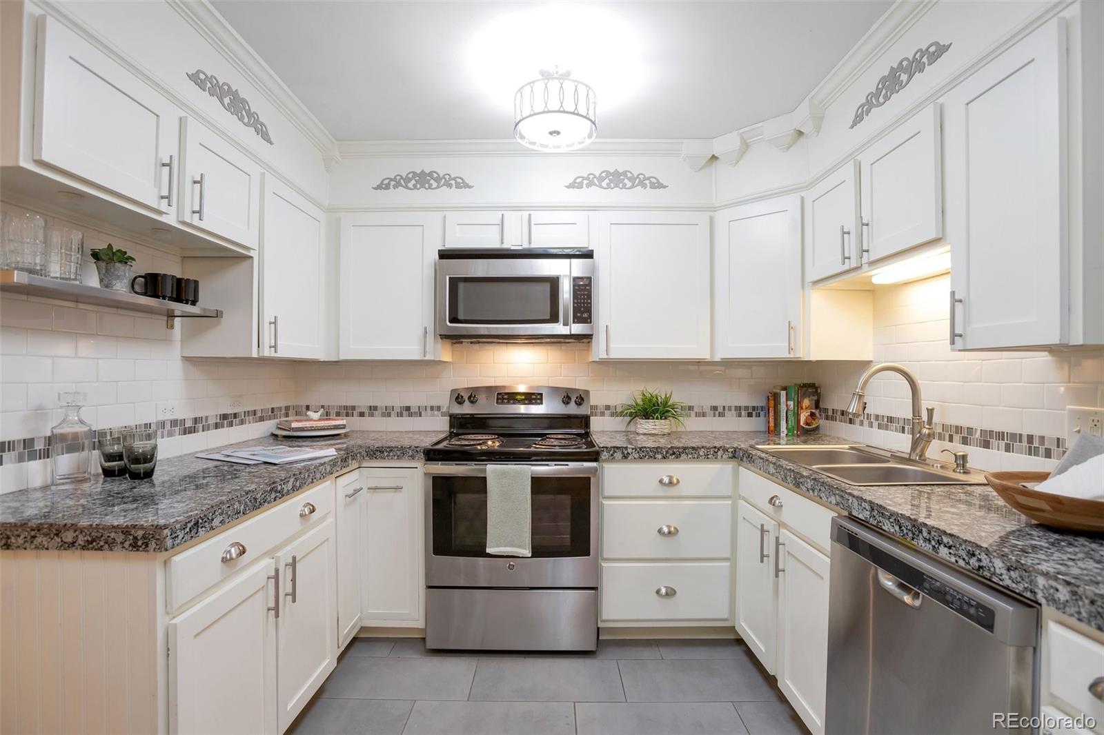 a kitchen with granite countertop white cabinets white stainless steel appliances with a sink and dishwasher