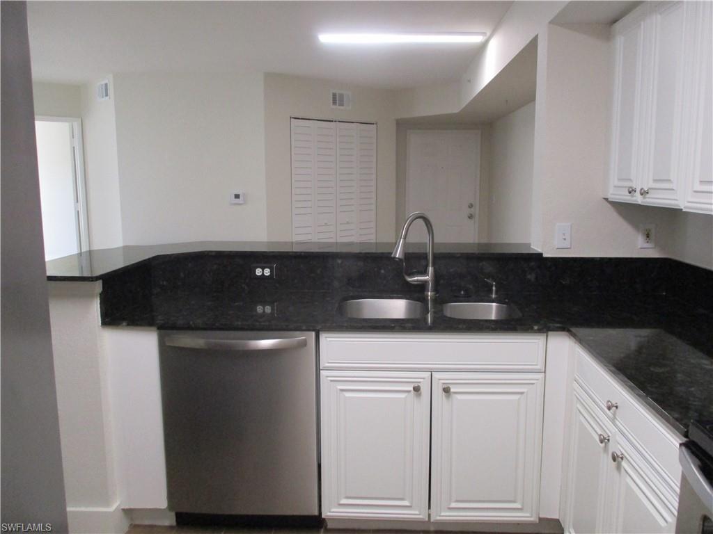 a kitchen with white cabinets and sink