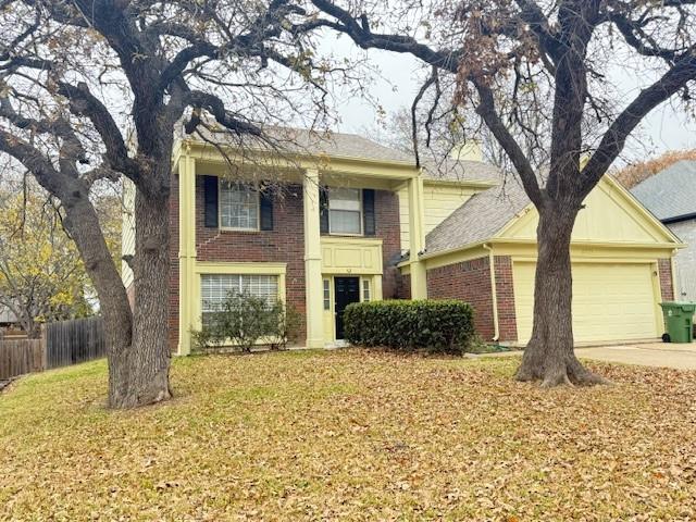 a front view of a house with a yard and large tree