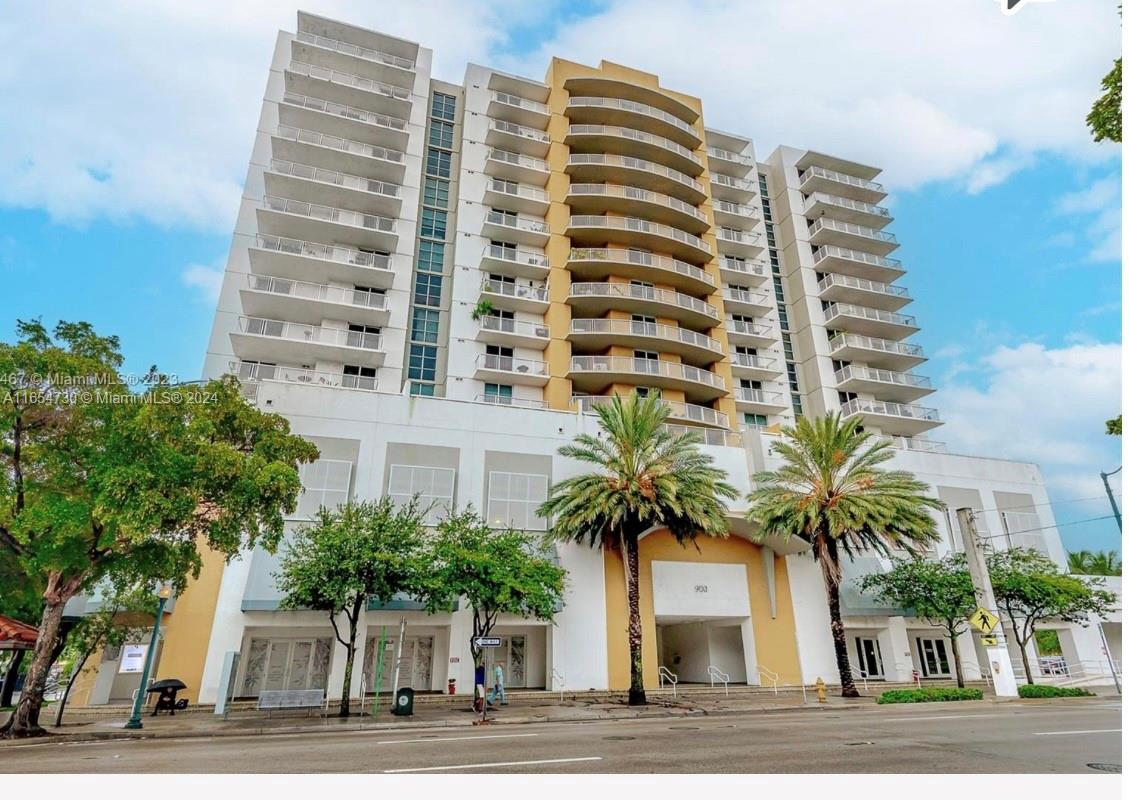 a front view of multi story residential apartment building with a palm tree in front