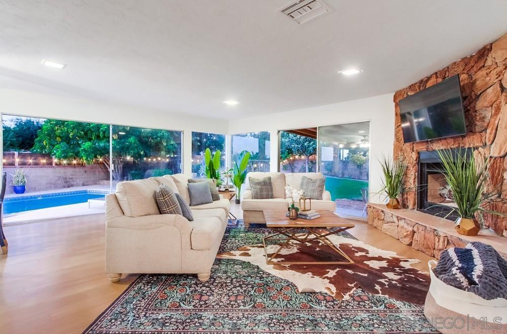 a living room with furniture wooden floor a lamp and a large window