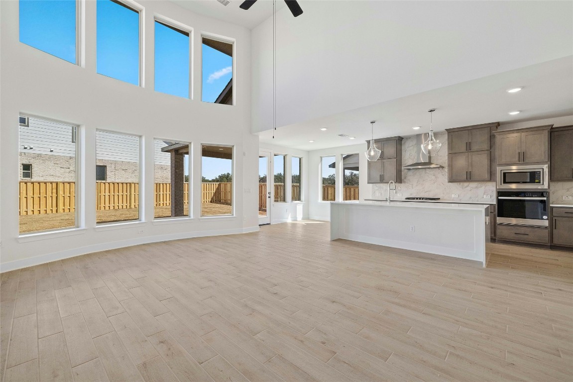 a view of an empty room with kitchen and window