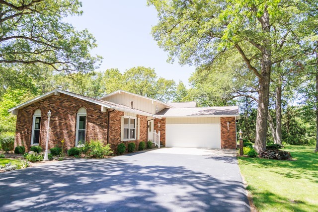 a front view of a house with a garden and tree