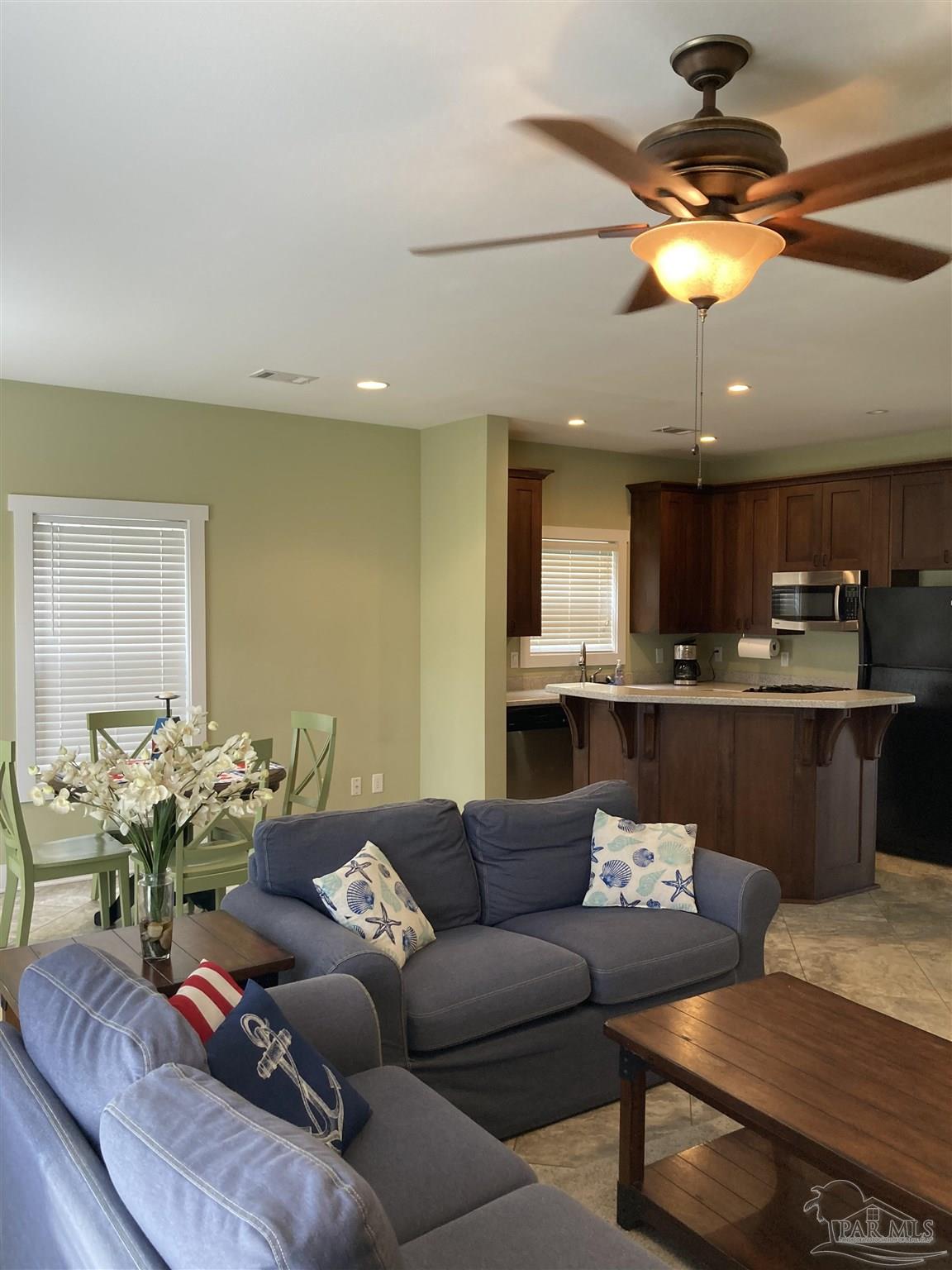 a living room with furniture kitchen view and a chandelier