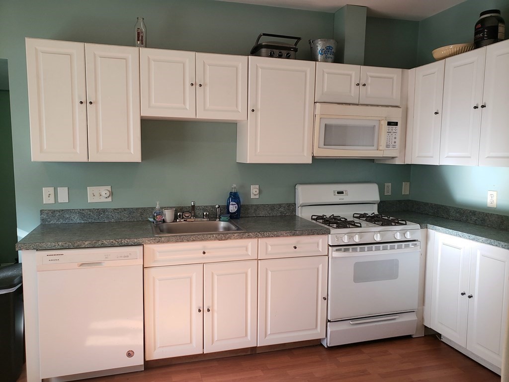 a kitchen with granite countertop white cabinets and white appliances