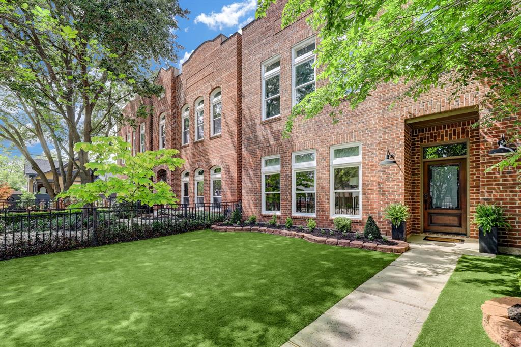 a view of a brick house with a yard and plants