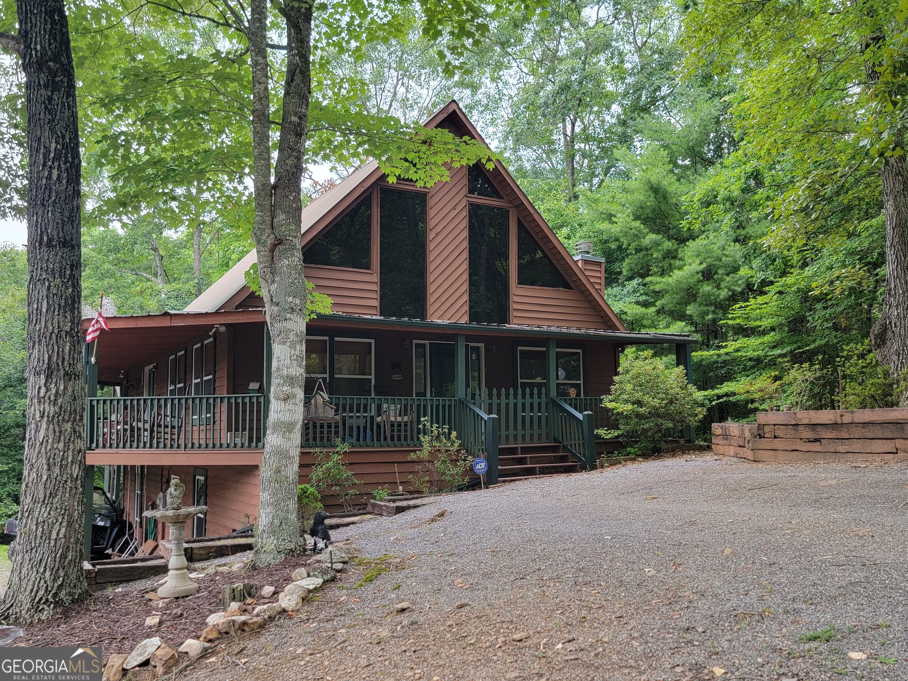 a view of a house with a yard plants and large tree