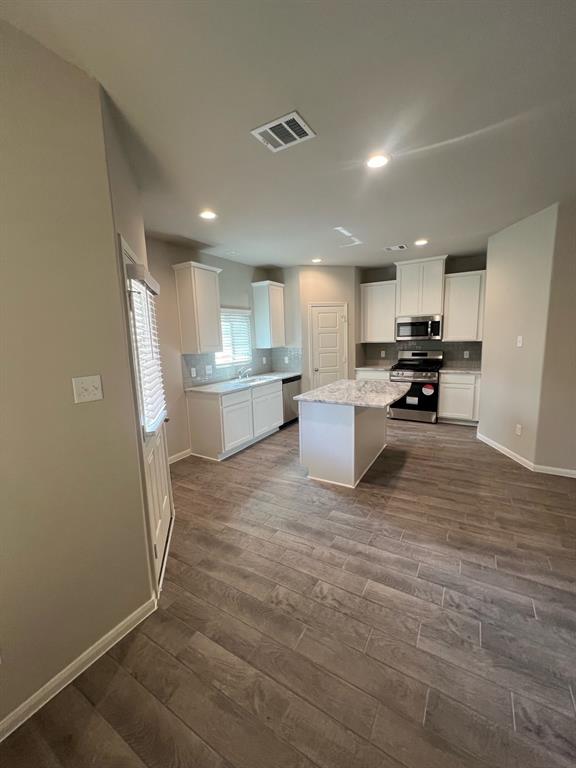 a room with stainless steel appliances granite countertop a refrigerator sink and cabinets