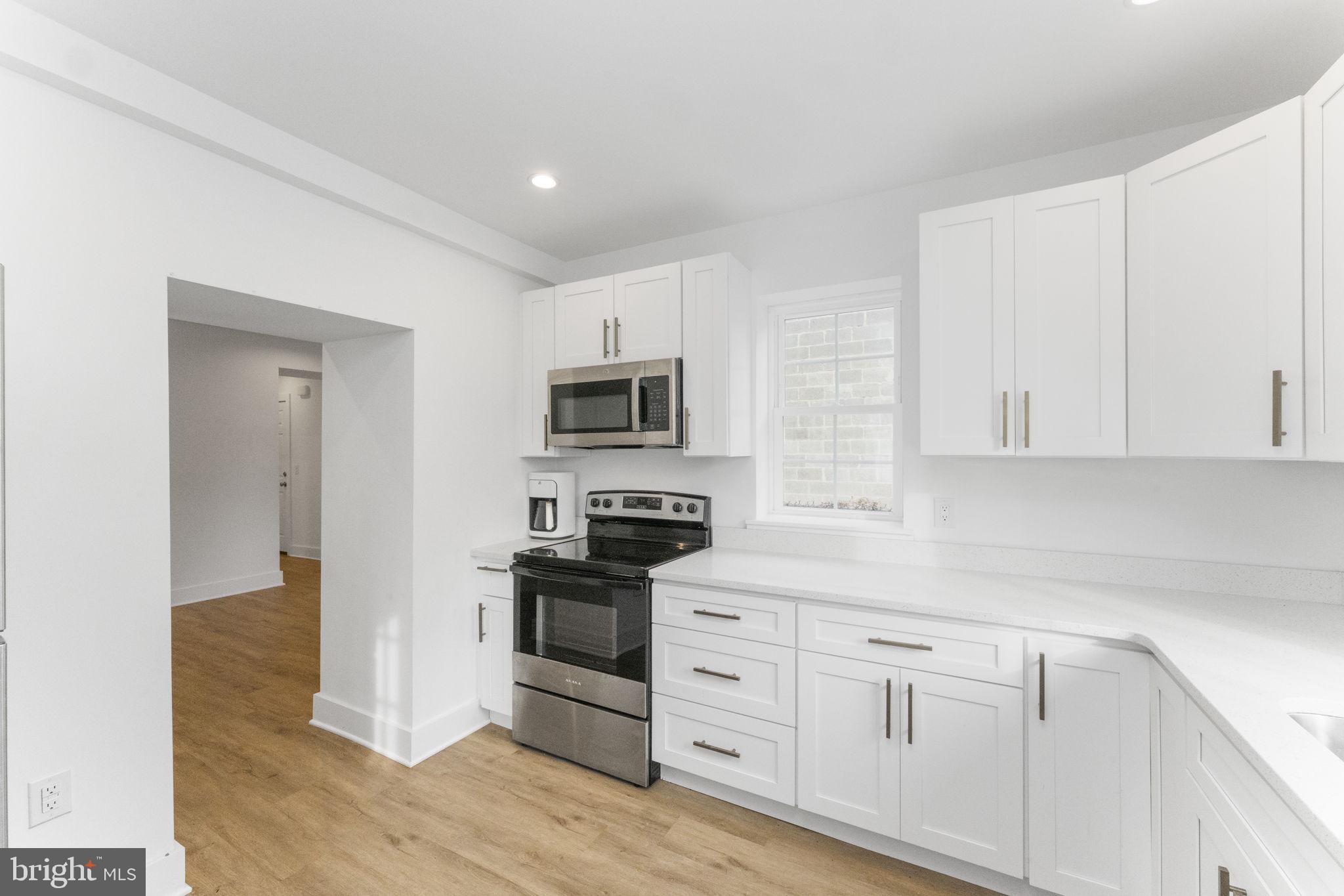 a kitchen with white cabinets stainless steel appliances and wooden floor