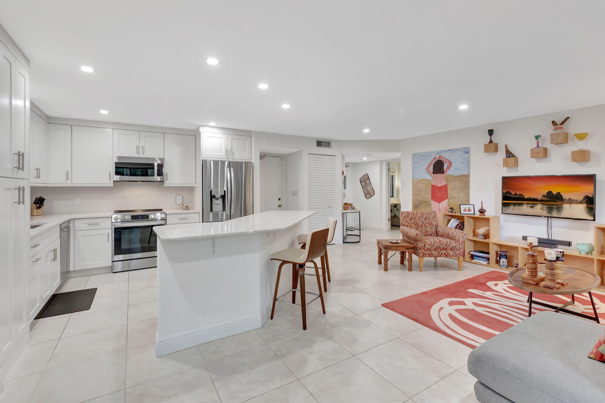 a living room with stainless steel appliances furniture and a kitchen view