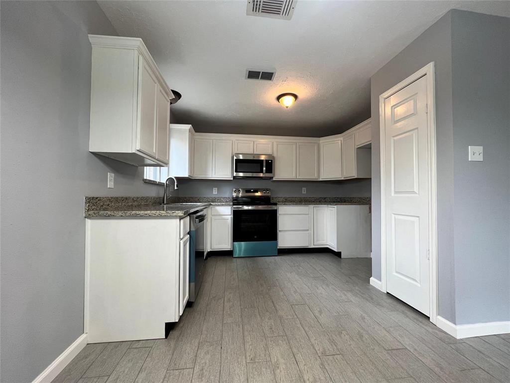 a kitchen with granite countertop white cabinets and stainless steel appliances