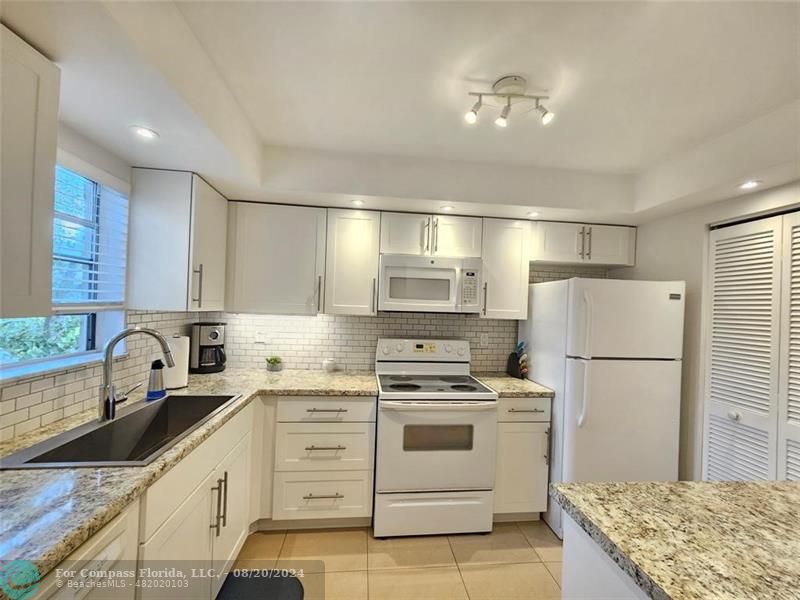 a kitchen with white cabinets and white appliances