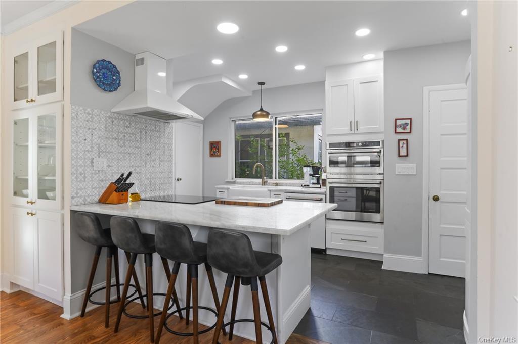 a kitchen with stainless steel appliances kitchen island granite countertop a table chairs sink and cabinets