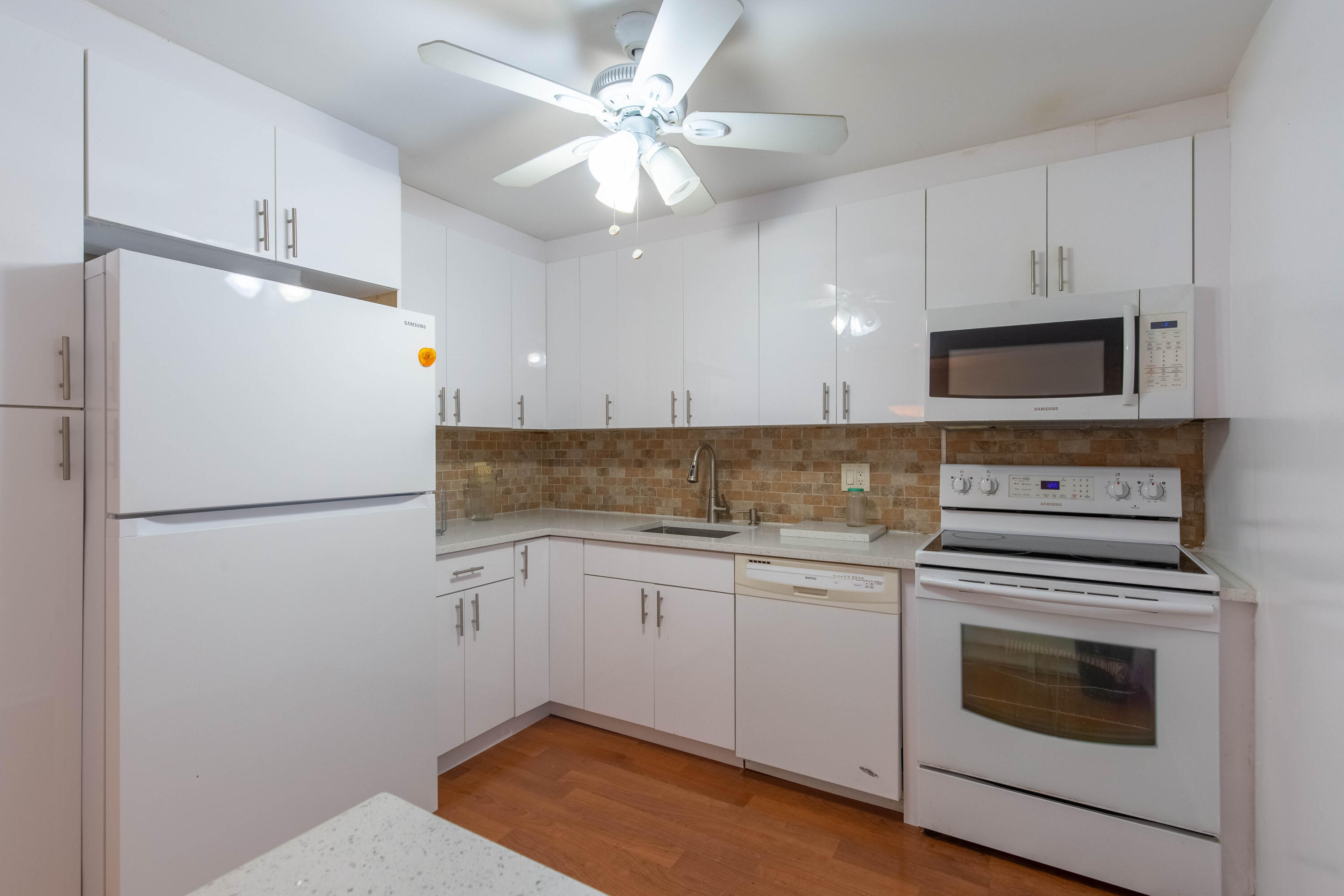 a white refrigerator freezer sitting inside of a kitchen with stainless steel appliances granite countertop cabinets and a refrigerator