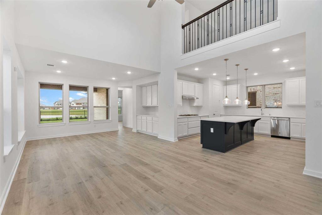 a large white kitchen with kitchen island a sink wooden floor stainless steel appliances and white cabinets