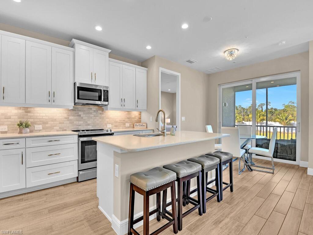 a kitchen with microwave a stove and chairs