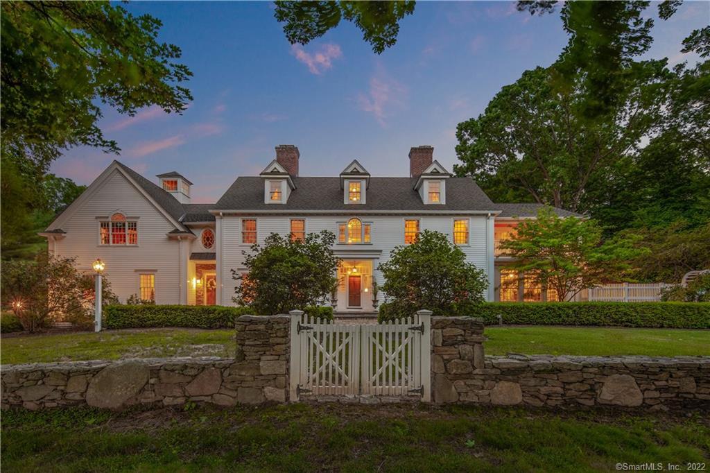 a view of a white house next to a yard with big trees