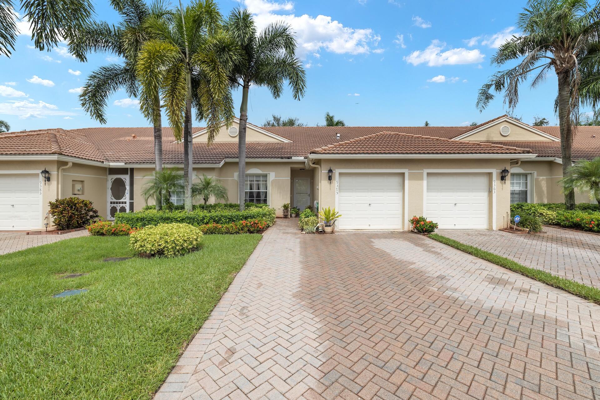 a front view of a house with a garden and palm trees