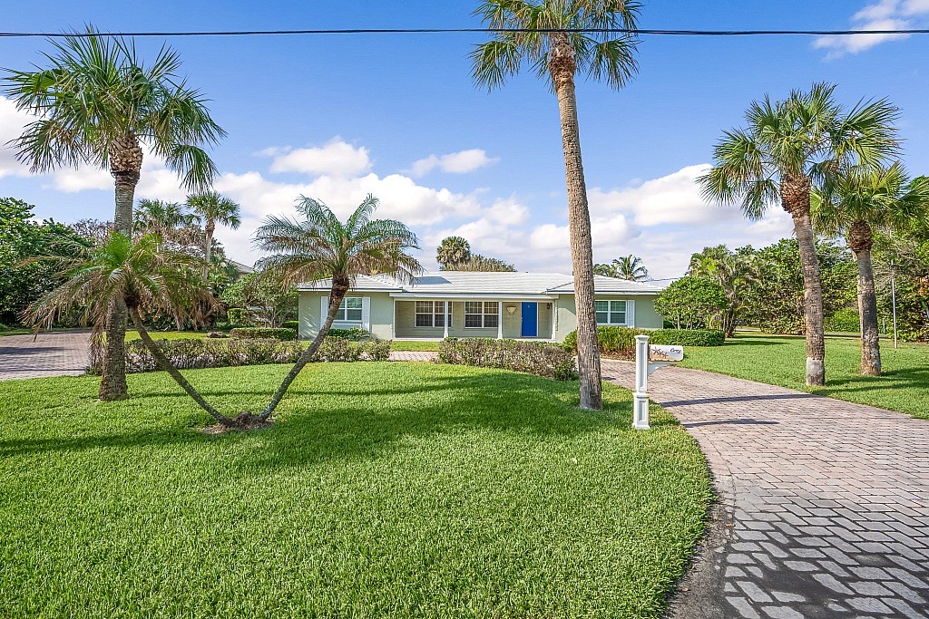 a view of a house with a yard and palm trees