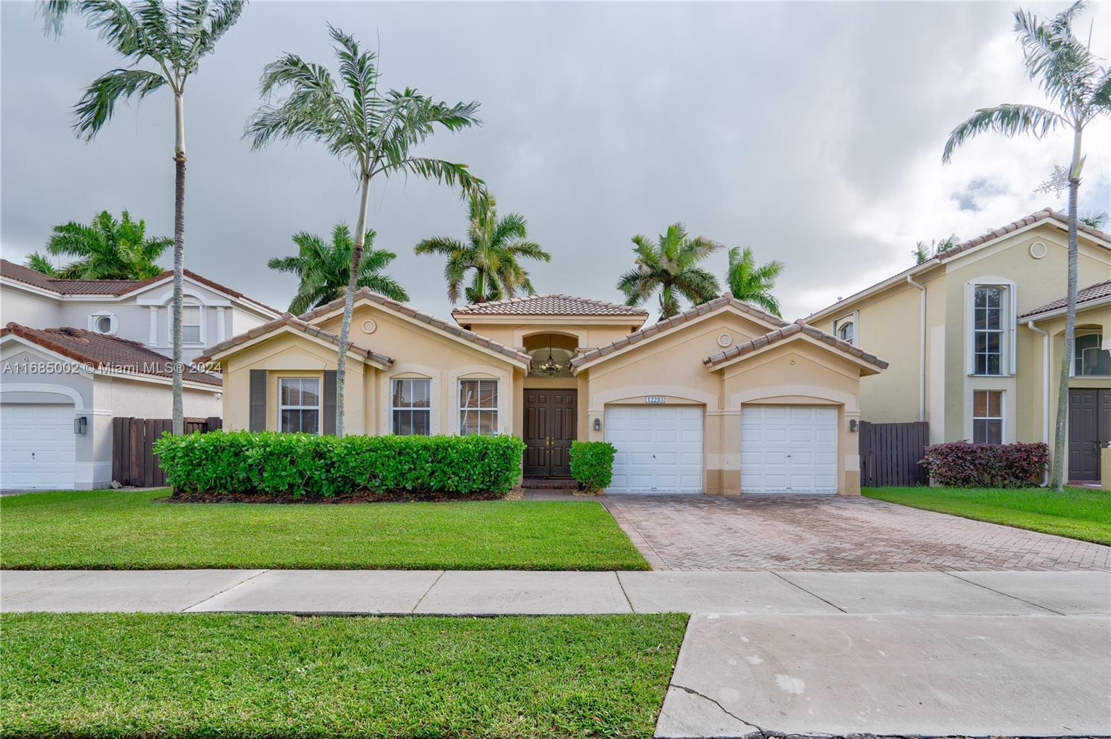 a front view of a house with a garden and palm trees