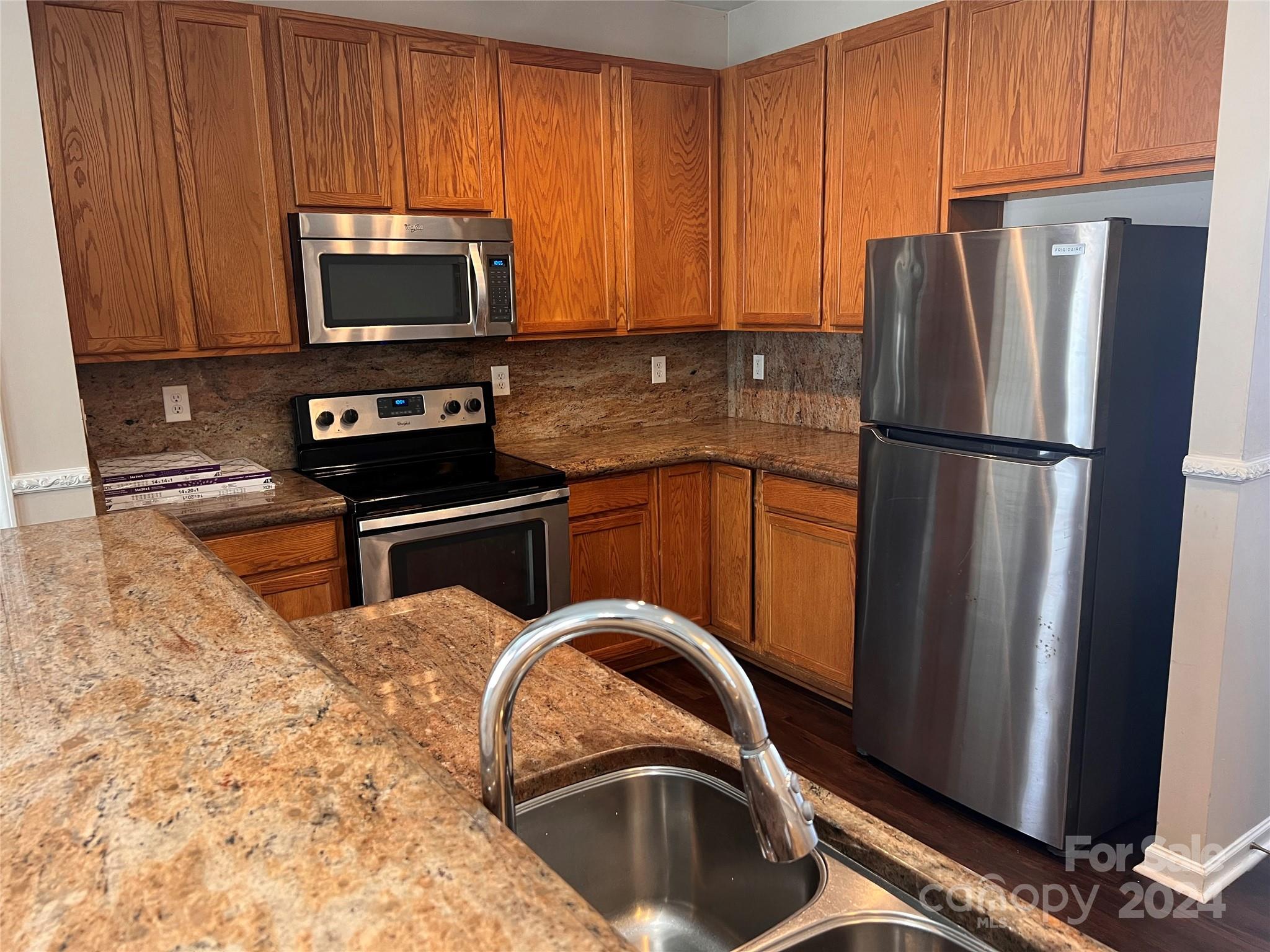 a kitchen with stainless steel appliances granite countertop a refrigerator stove and microwave