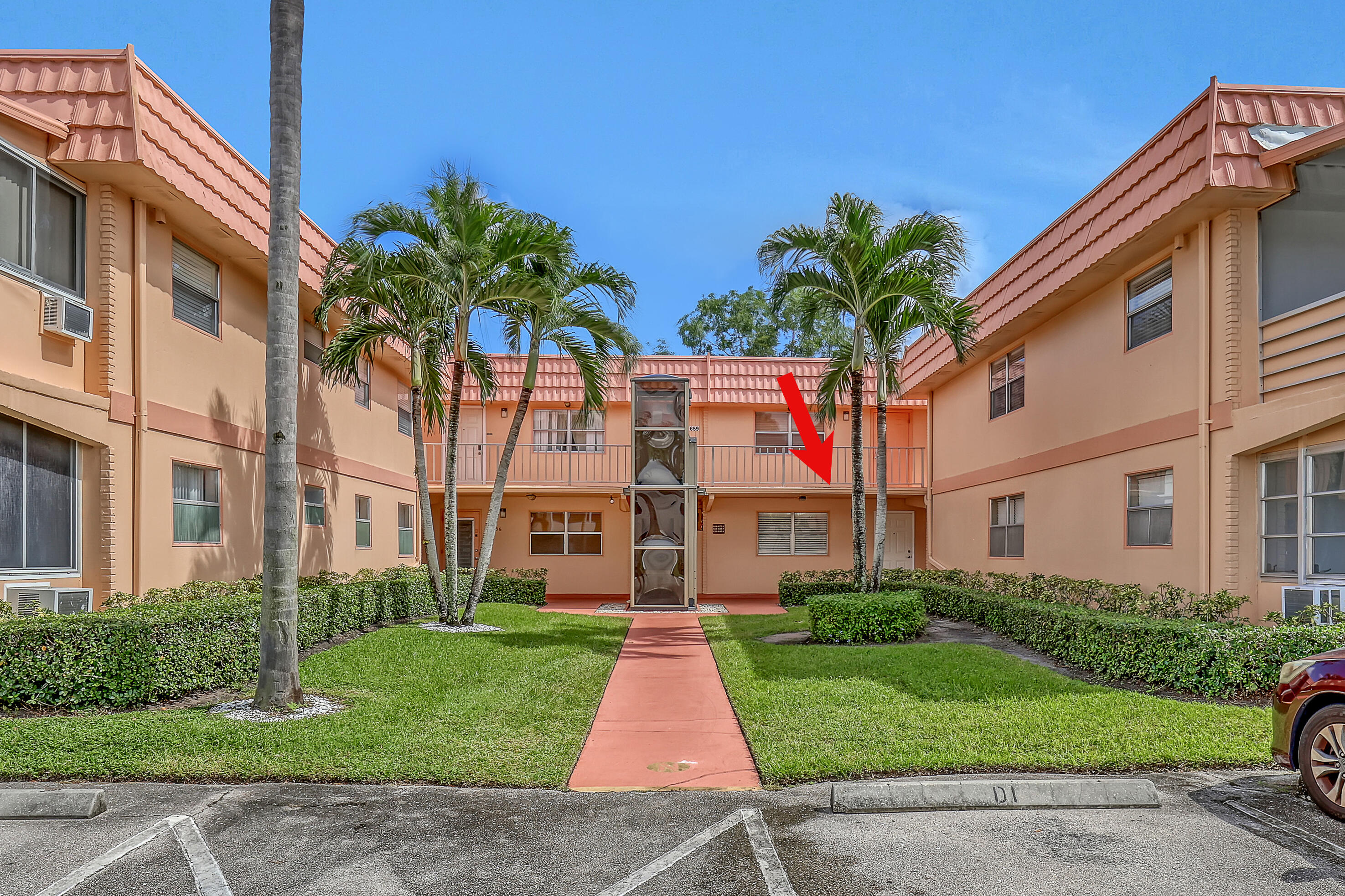 a front view of a multi story residential apartment building with yard and green space