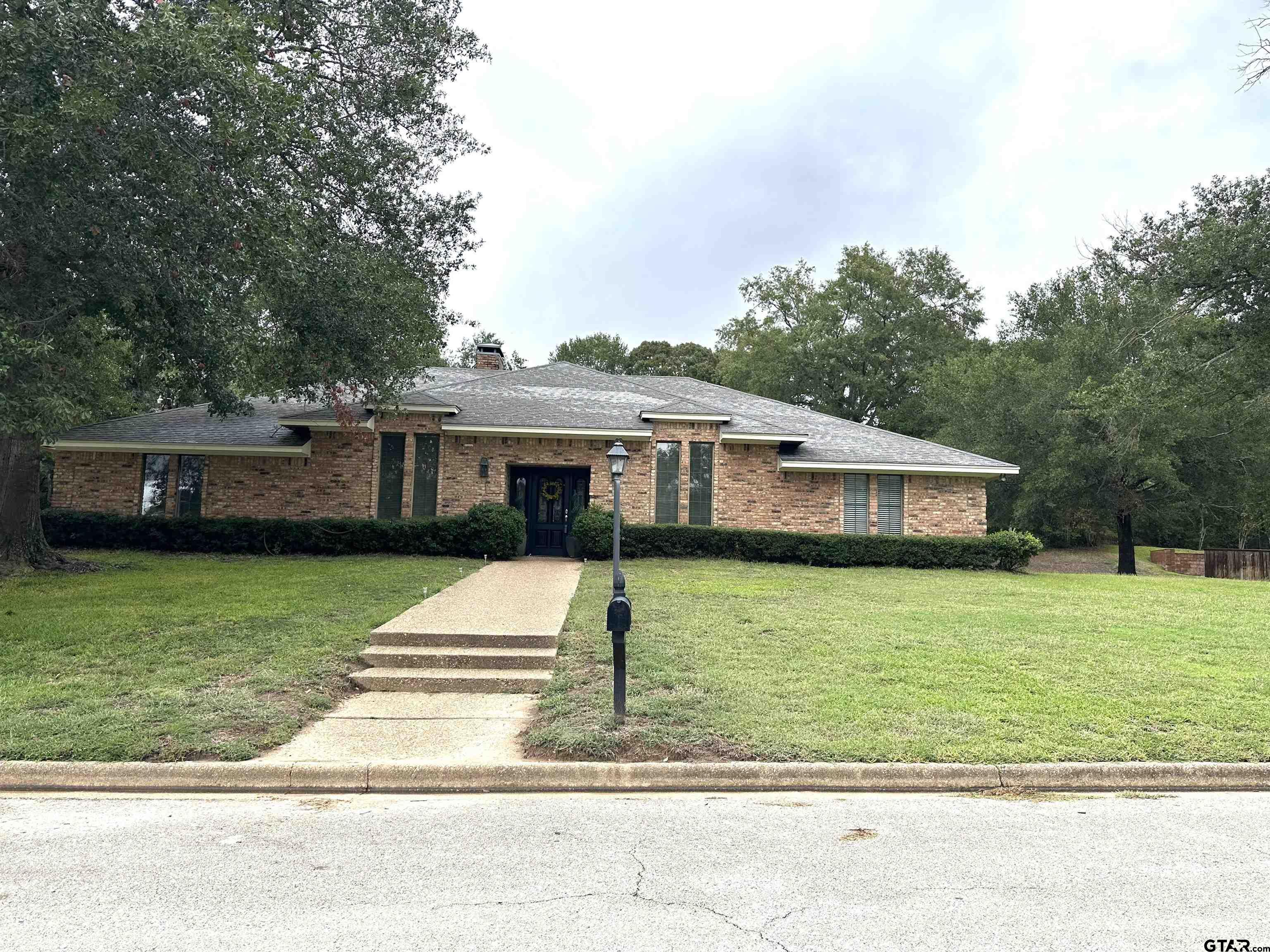 a front view of a house with a garden and trees