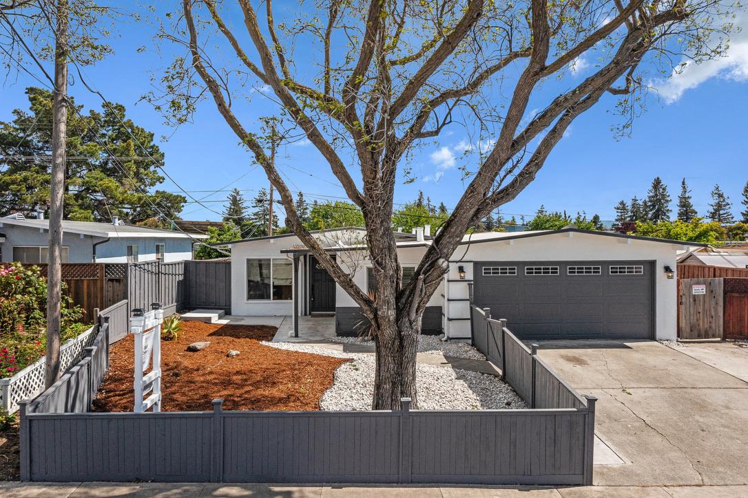 a view of a house with wooden fence next to a large tree