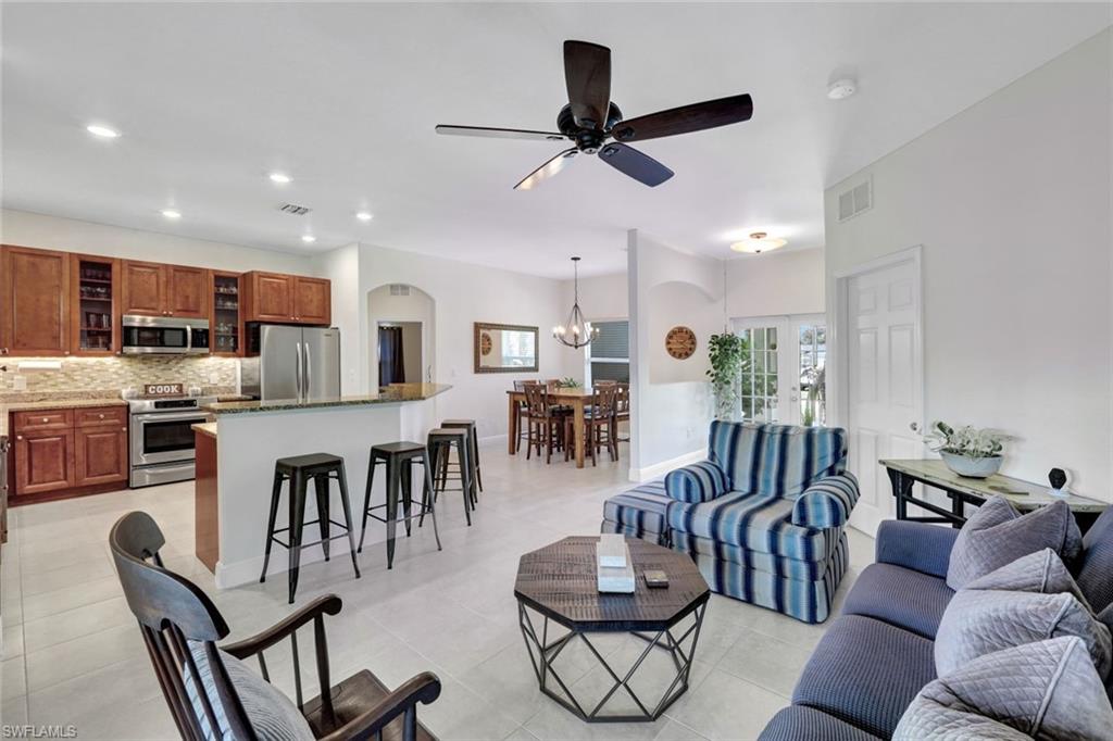 Tiled living room with ceiling fan with notable chandelier and a wealth of natural light