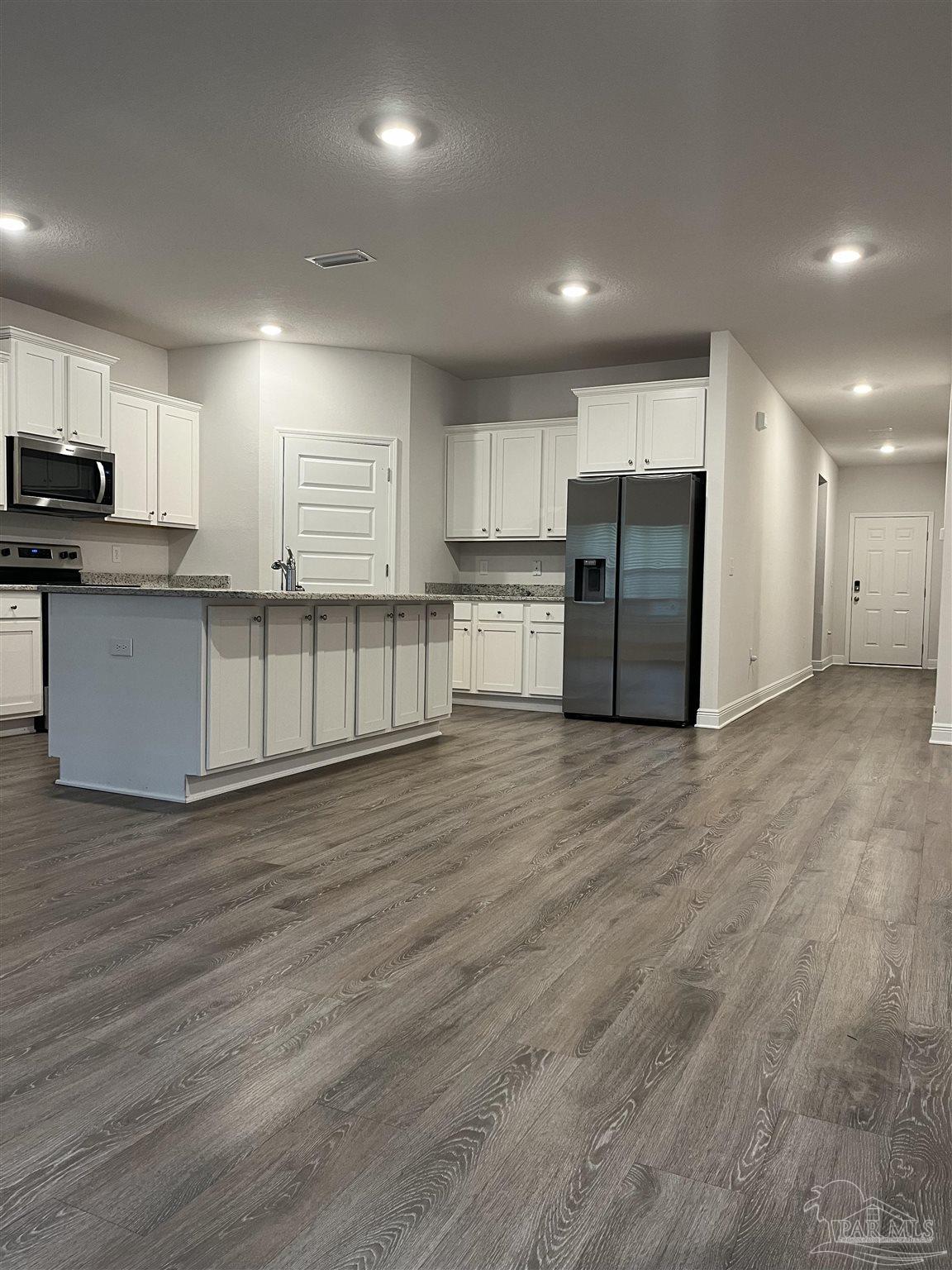 a view of kitchen with kitchen island microwave and cabinets