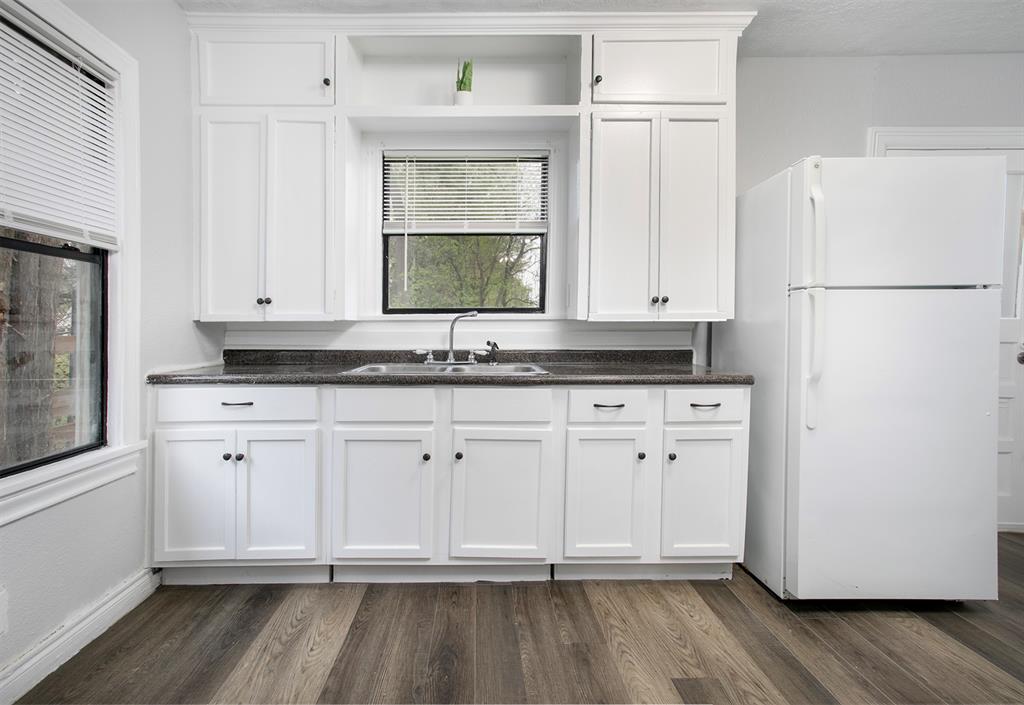 a kitchen with granite countertop a refrigerator sink and cabinets