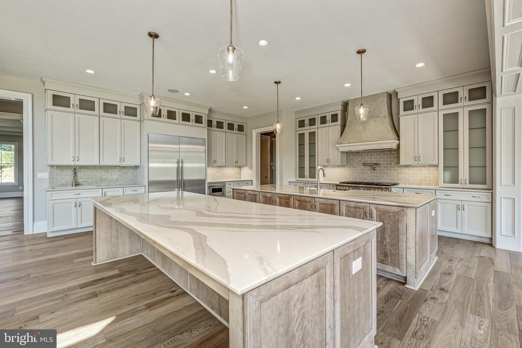 a large kitchen with kitchen island a stove a sink a center island and wooden floor