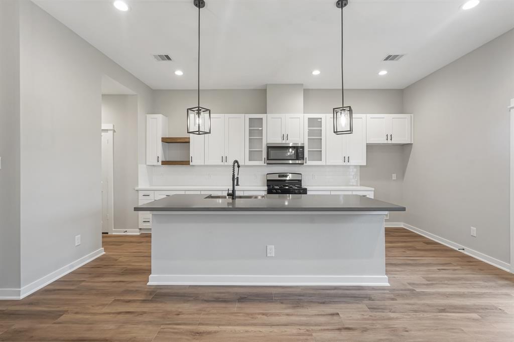 a large kitchen with granite countertop a stove a sink and white cabinets