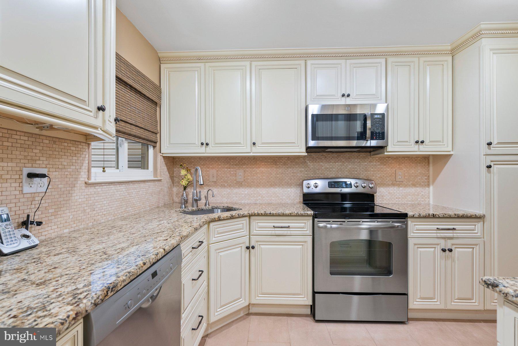 a kitchen with granite countertop white cabinets and white stainless steel appliances