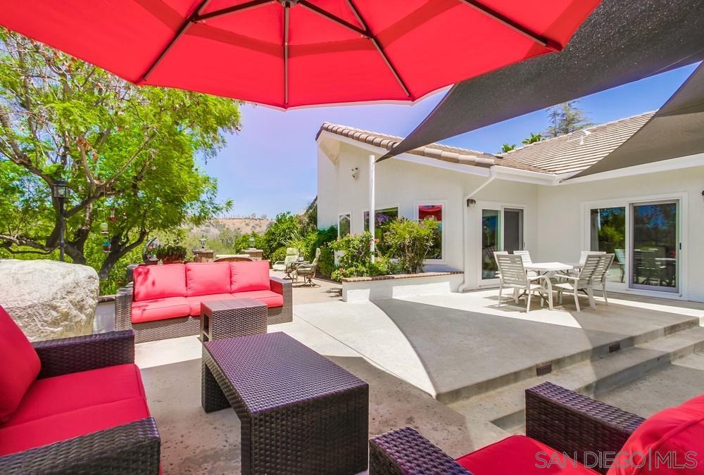 a view of a patio with couches table and chairs under an umbrella