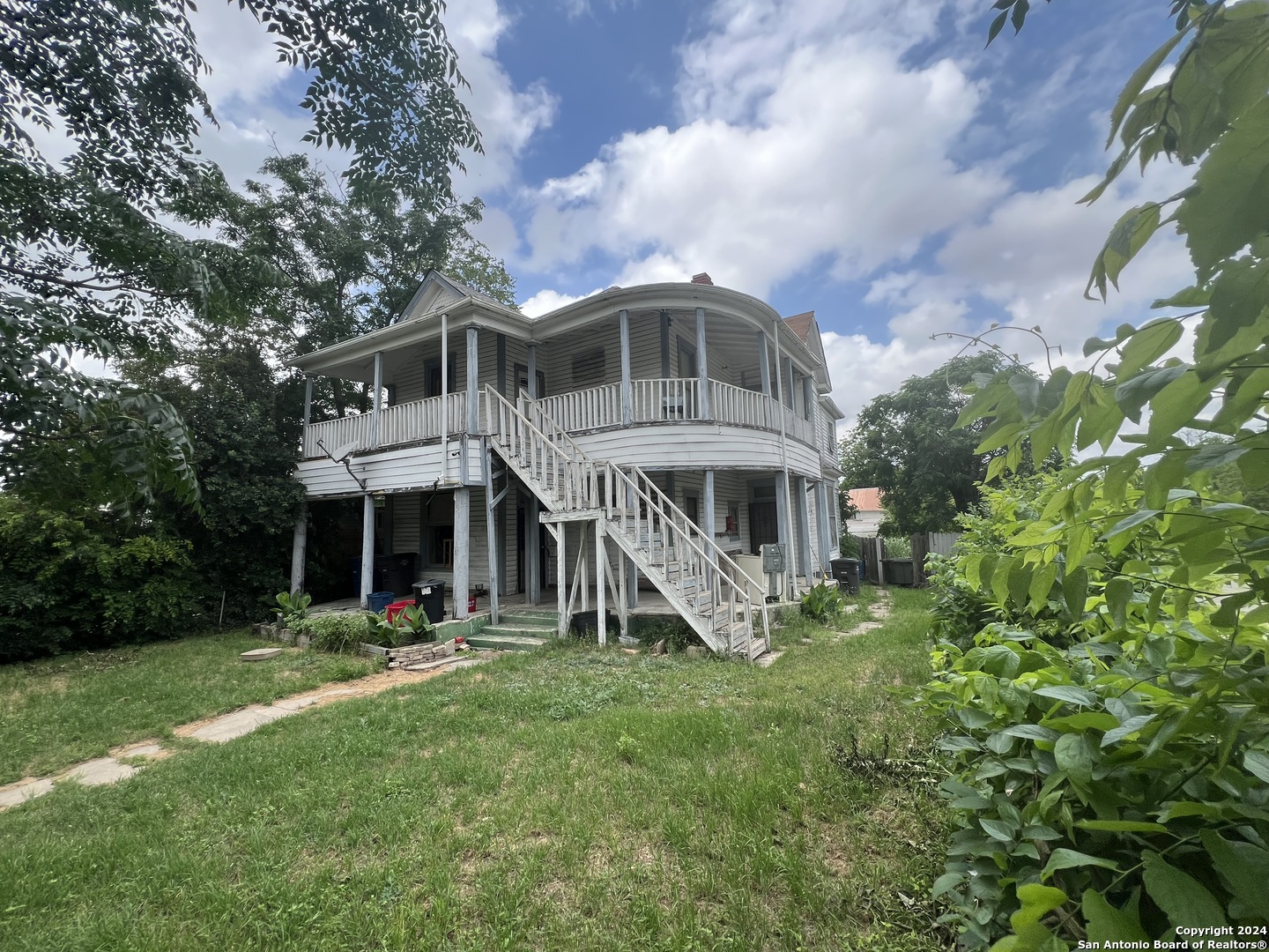 a view of a house with a big yard and large trees