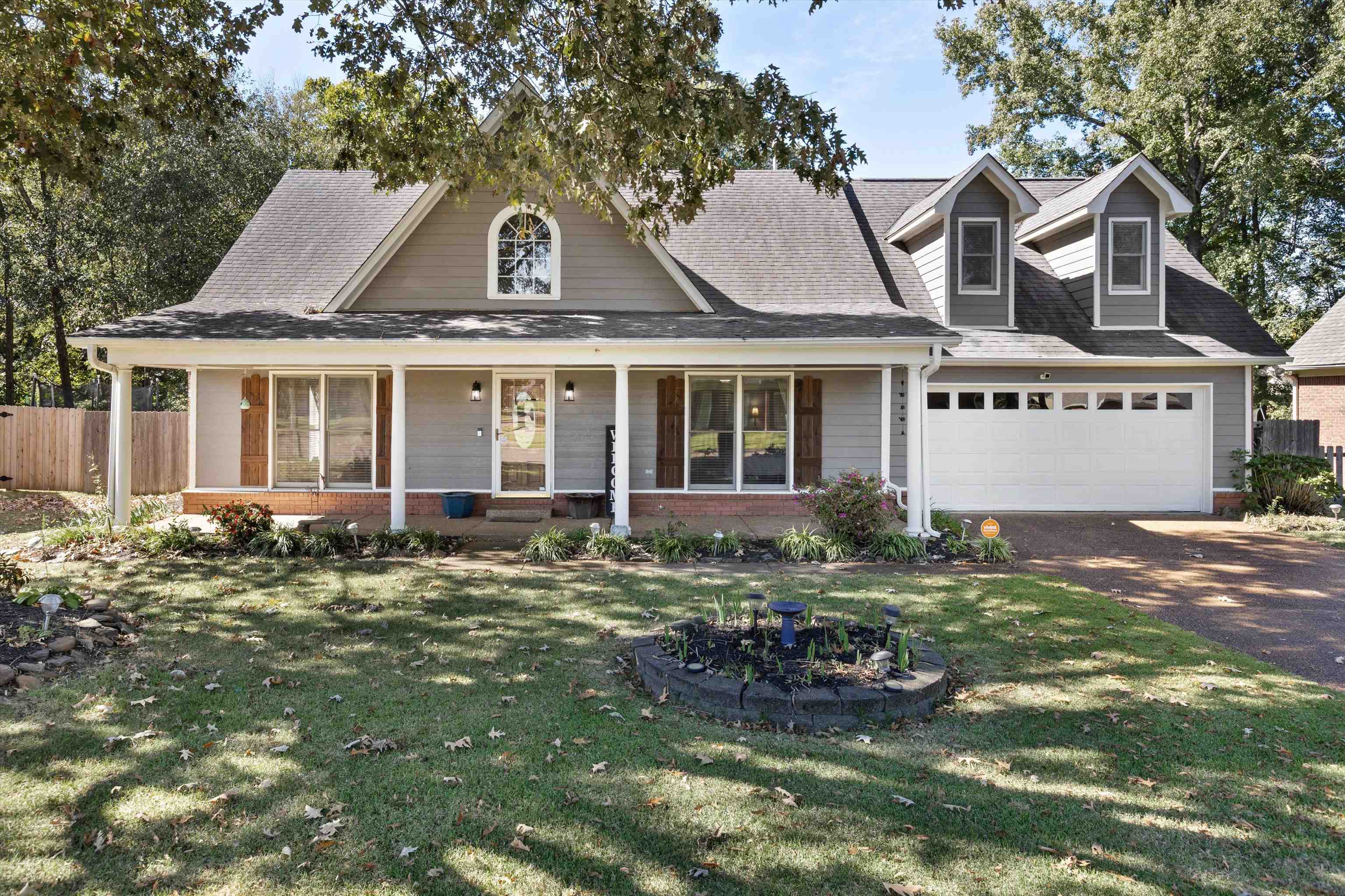 View of front of home with a front lawn, covered porch, and a garage